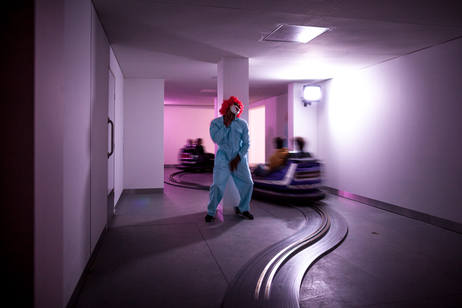 Bumper cars driving past a dancing clown. 