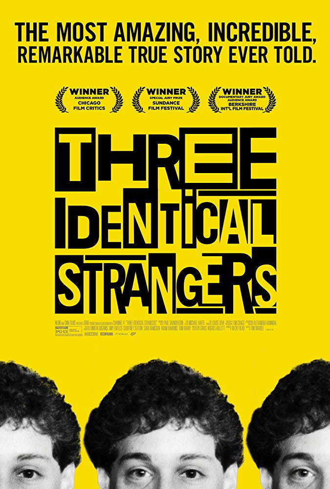 The film poster showing the top halfs of the heads of three guys in front of a yellow background. 
