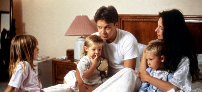 A family - father, mother and three children - together in bed.