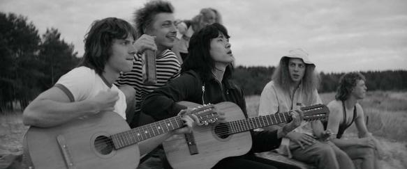 Viktor Tsoy (Teo Yoo) singing with a couple of guys at the beach. 