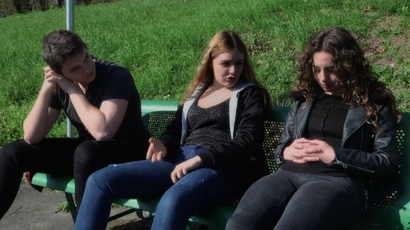 Two teenage girls and a teenage boy talking.