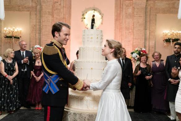 Amber (Rose McIver) and Richard (Ben Lamb) standing in front of a big wedding cake.