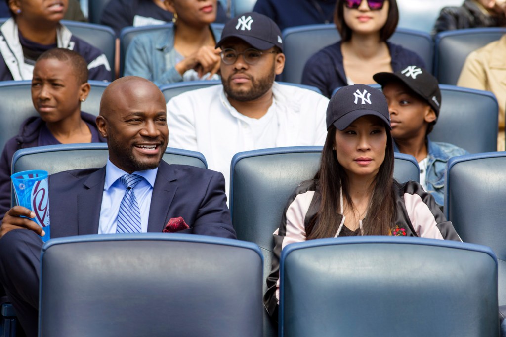 Rick (Taye Diggs) and Kirsten (Lucy Liu) at a sports game.