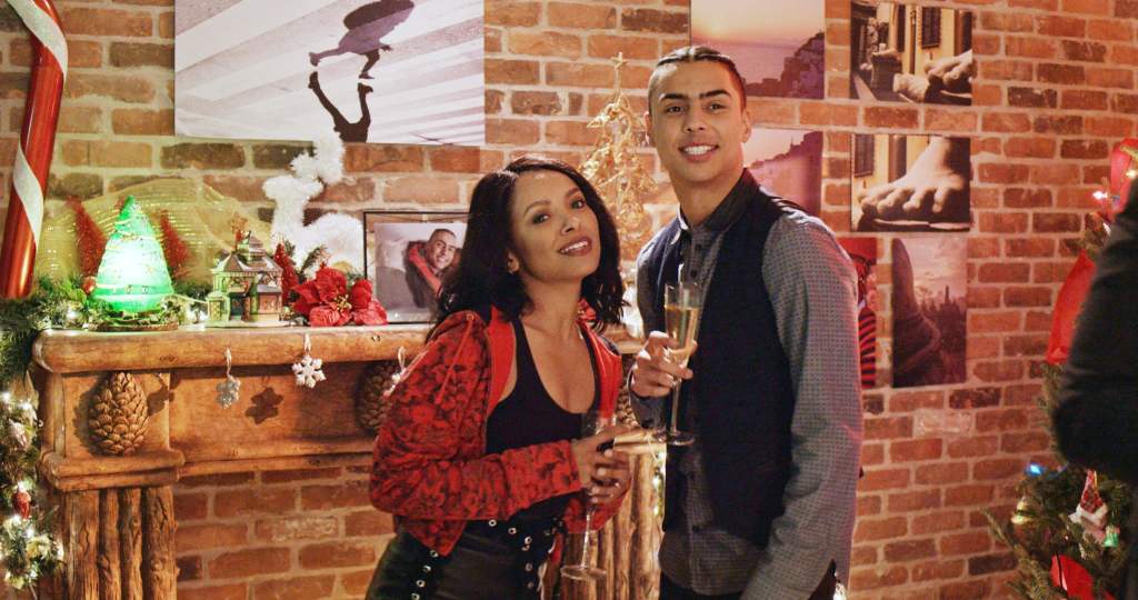 A young woman (Kat Graham) and a young man (Quincy Brown) standing in front of a decorated fireplace.