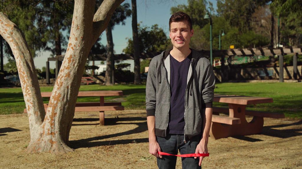 A young man in a park looking awkward.