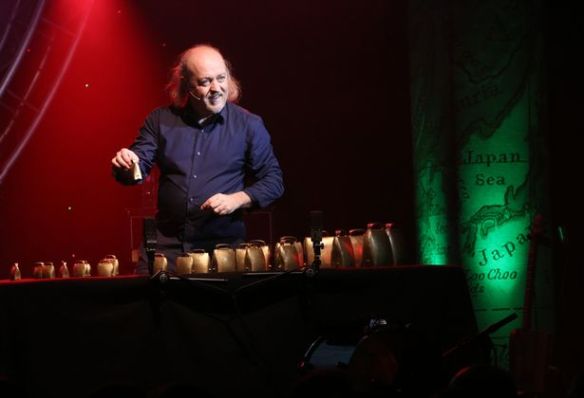 Bill Bailey playing a table full of cowbells.