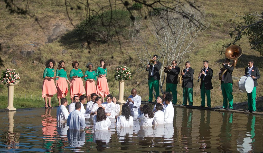 Adults in a natural swimming pool getting baptized.