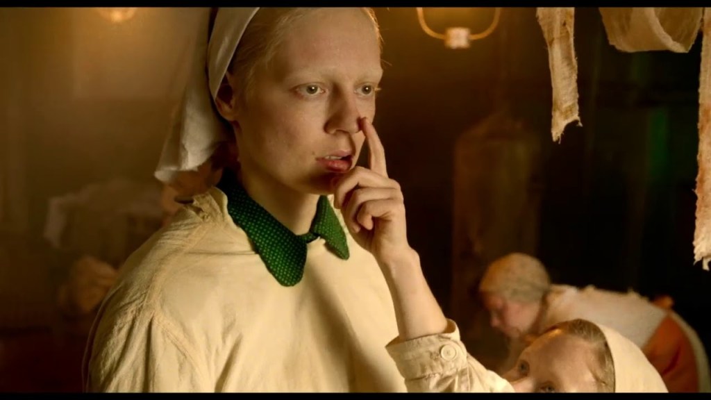  Iya (Viktoria Miroshnichenko) standing slack-faced, a child touching her nose with a finger. 