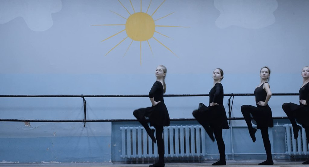 A group of girls taking ballet lessons, dressed in black. 
