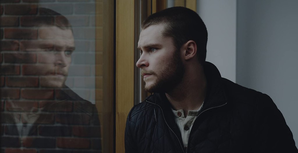 John (Jack Reynor) looking out the window.