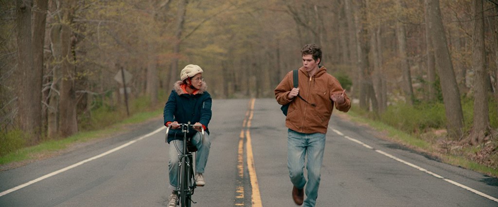 Ellie (Leah Lewis) cycles and Paul (Daniel Diemer) runs alongside her.