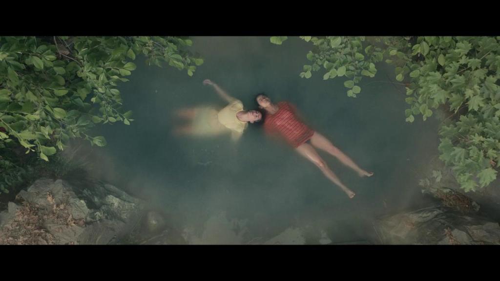 Ellie (Leah Lewis) and Aster (Alexxis Lemire) floating in a natural pool.