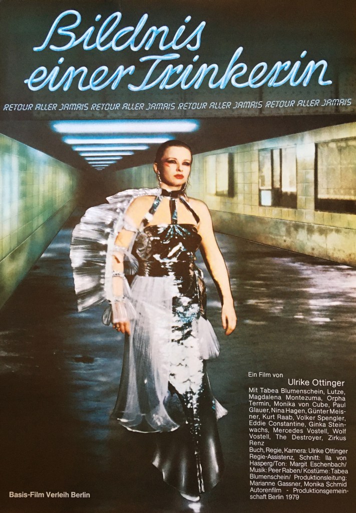 The film poster showing the protagonist (Tabea Blumenschein) walking through a hallway underground in an extravagant, futuristic dress. 