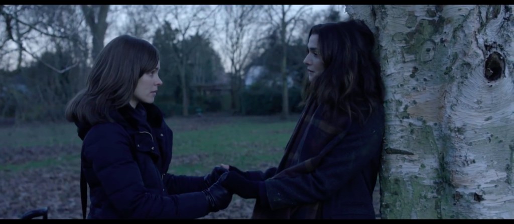 Esti (Rachel McAdams) and Ronit (Rachel Weisz) holding hands in a park.