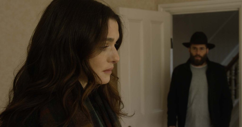 Ronit (Rachel Weisz) looks sad, Dovid (Alessandro Nivola) watches her.