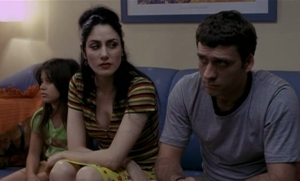 Zaza (Lior Ashkenazi) and Judith (Ronit Elkabetz) on the sofa as they face his family.