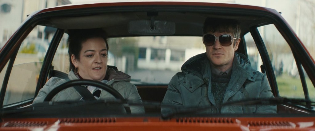 Rose (Maeve Higgins) sitting in her car with Martin (Barry Ward).