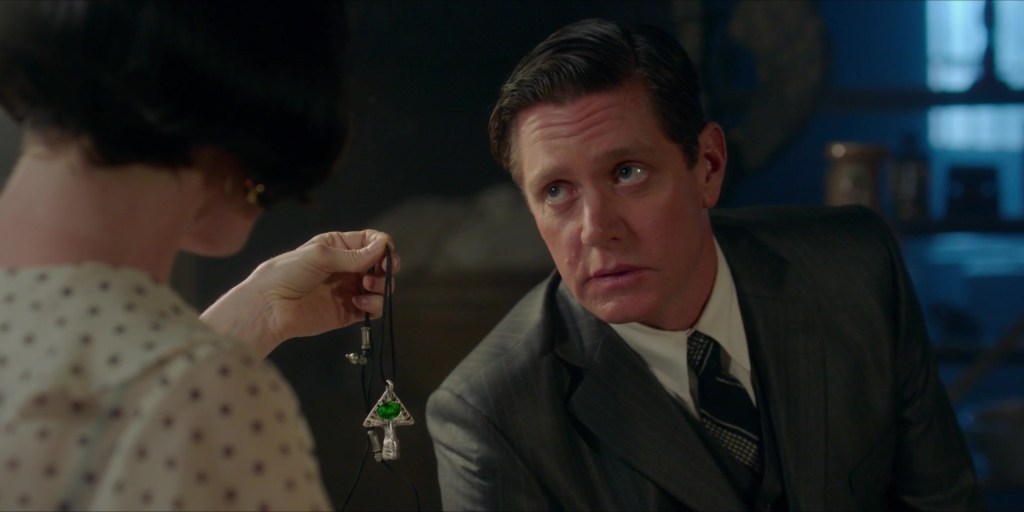 Phryne Fisher (Essie Davis) holds up a necklace to Jack Robinson (Nathan Page).
