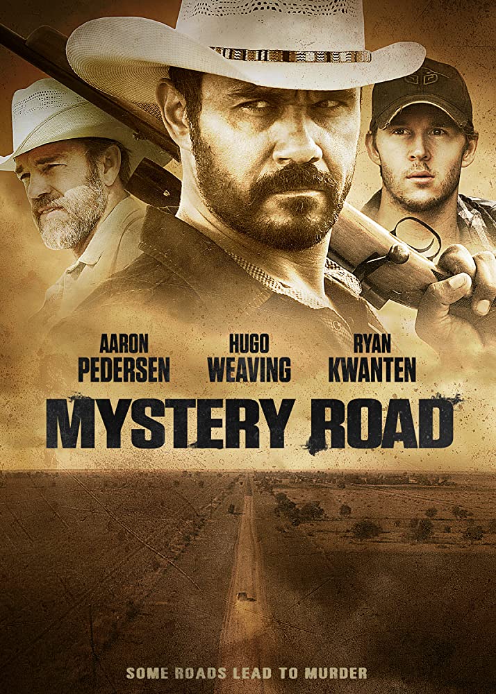The film poster showing a lone car on a dirt road and the heads of three of the main characters.