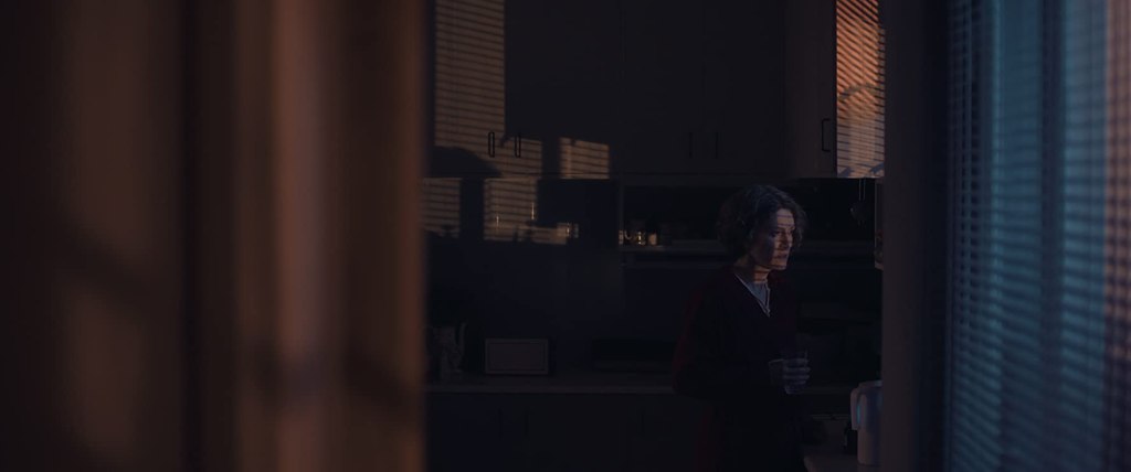 Elpida (Stella Fyorgeni) looking out the window in the dark. 