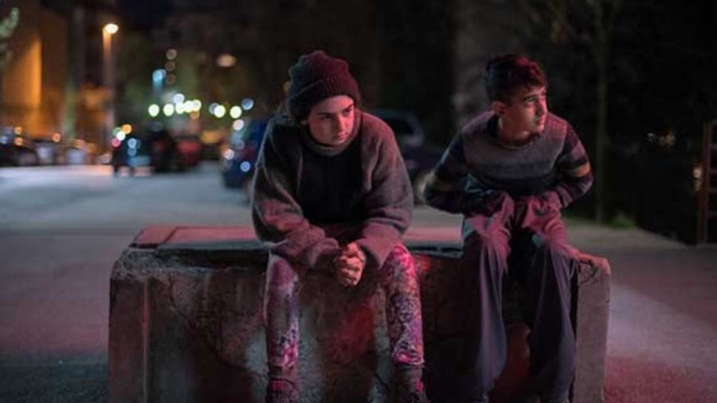 Two dishevelled teens sitting outside.