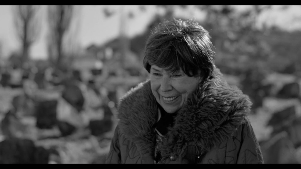 An old woman visiting a cemetery.