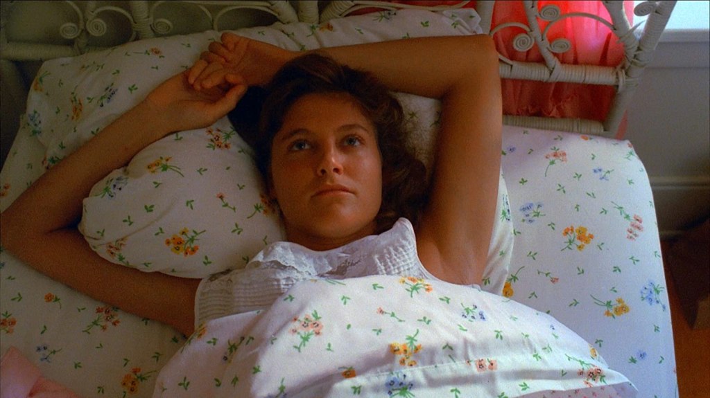 Trish (Michelle Michaels) lying in bed.