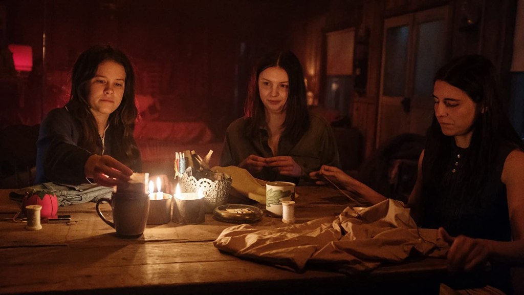 Susan (Marianne Rendón), Leslie (Hannah Murray) and Patricia (Sosie Bacon) doing some needlework around a table. 