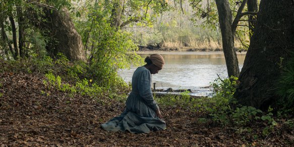 Harriet (Cynthia Erivo) kneeling under a tree, praying.