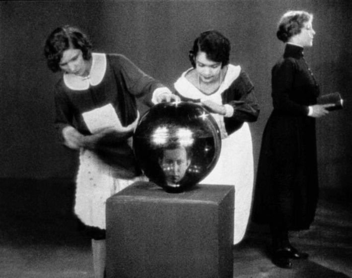 Two maids polishing a giant reflective orb.