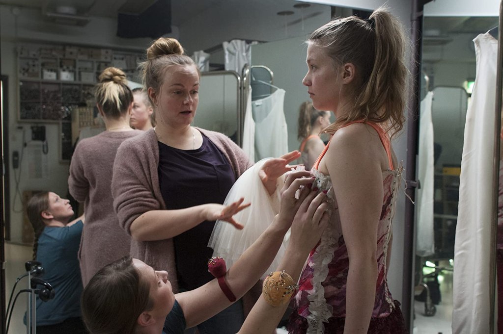Emppu (Julia Lappalainen) in the dressing room, having her clothes fitted for the play. 