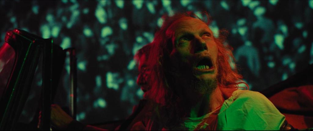 Barry (Gary Green) in acar, watching his psychedelic surroundings with his mouth open.