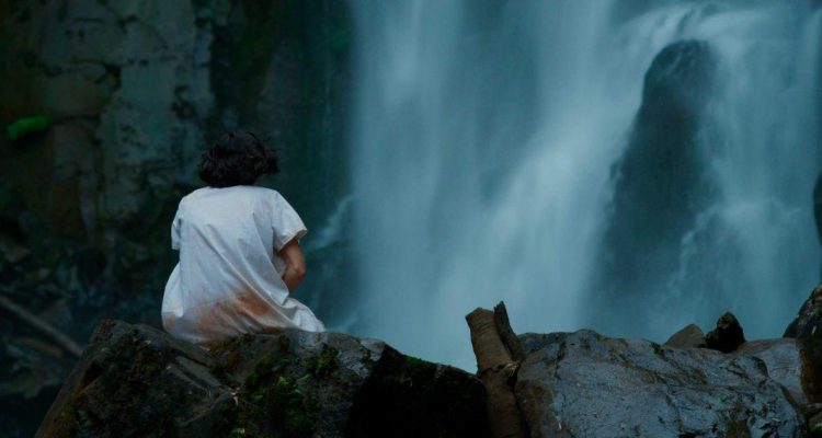 Julia (María Soldi) sitting at the foot of a waterfall with a bloody night-gown. We see her only from behind, cradling something. 