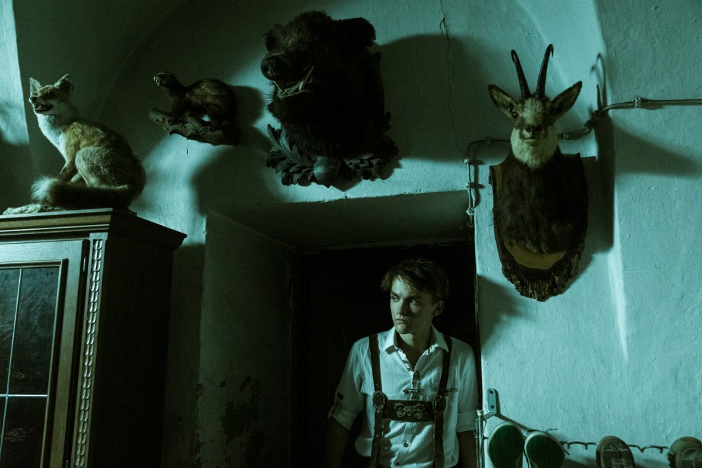Hendrik ( Leon Orlandianyi) in a dark room filled with hunting trophies. 