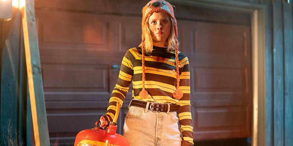 Becky (Lulu Wilson) witha  can of gas in front of a garage door.