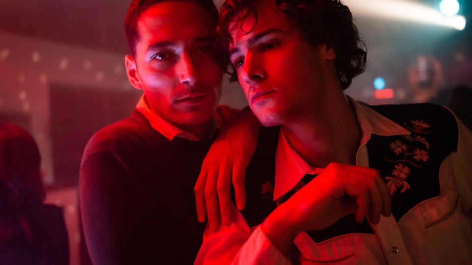 Lenz (Noah Saavedra) and Mario (Thomas Prenn) in a bar, leaning against each other. 