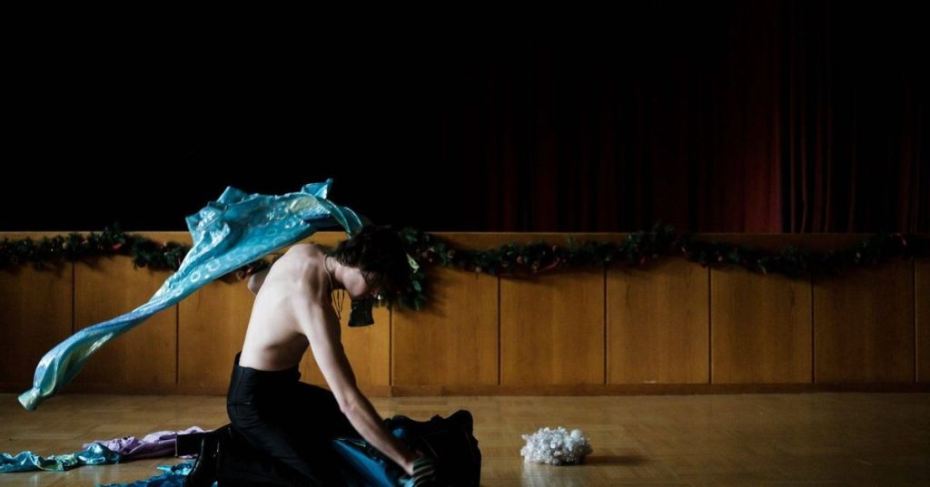 Mario (Thomas Prenn) tearing through a bag of clothes in his rehearsal space.