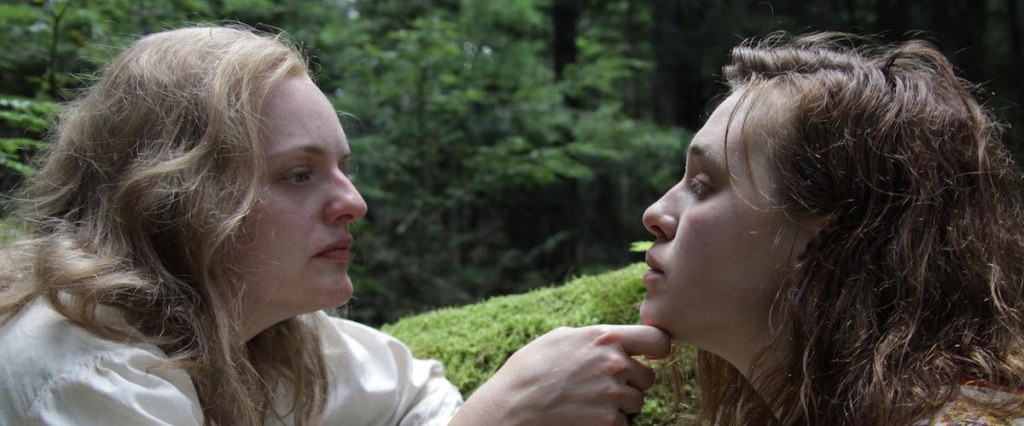 Shirley (Elisabeth Moss) and Rose (Odessa Young) in the forest. Shirley is grabbing Rose's chin.