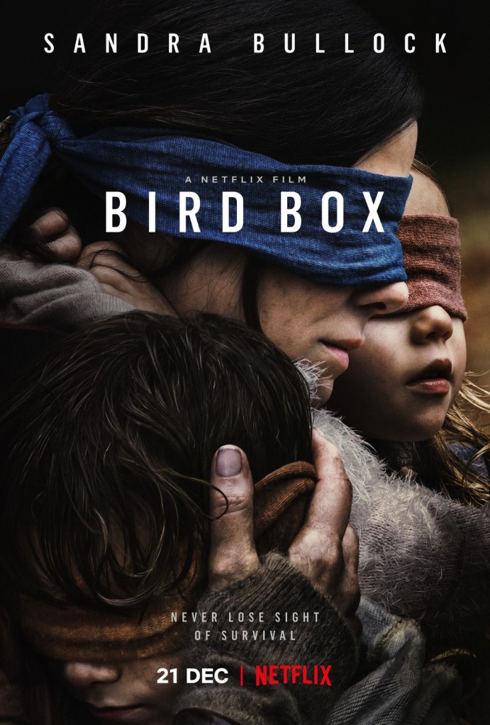 The film poster showing Malorie (Sandra Bullock) with blindfolded eyes, cradling both her children who are also blindfolded.