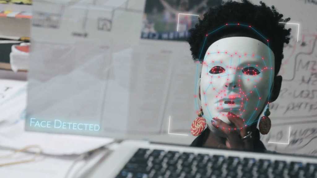 Joy Buolamwini tricking a face tracking software by wearing a white mask.