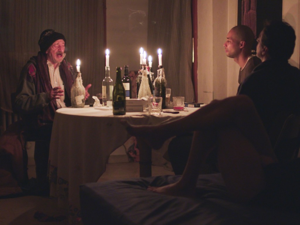 Bianca and her friends sitting around a table luminated by candles. One of them is singing.