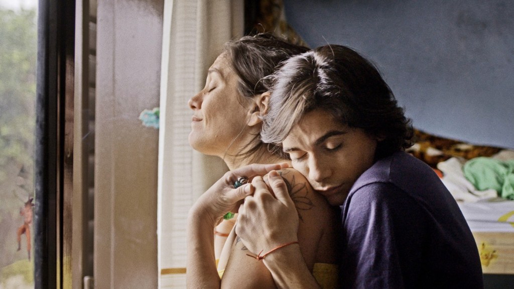 Darío (Mauricio Vila) hugging his mom from behind. 