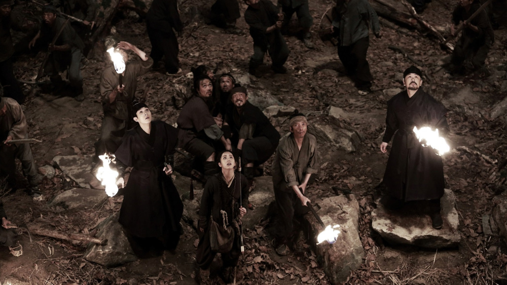 A group of people with torches looking up in the sky, obviously scared. 