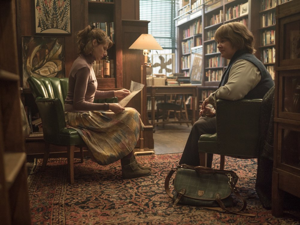 Anna (Dolly Wells) reading a letter that Lee (Melissa McCarthy) brought her in her bookshop.