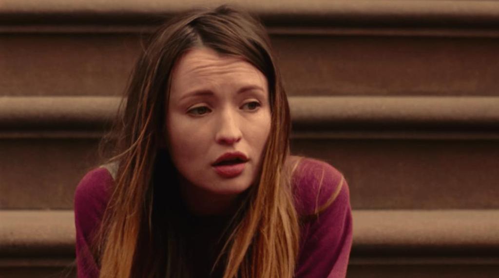 Naomi (Emily Browning) sitting on some stairs outside.