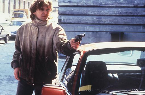 Robert (Hansi Lang) pointing a gun at someone or something.