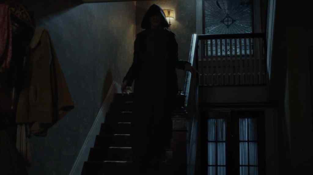 The Bye Bye Man (Doug Jones) - a hooded figure whose face you can't see - coming down the stairs.