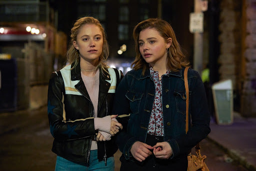 Frances (Chloë Grace Moretz) walking arm in arm with Erica (Maika Monroe).