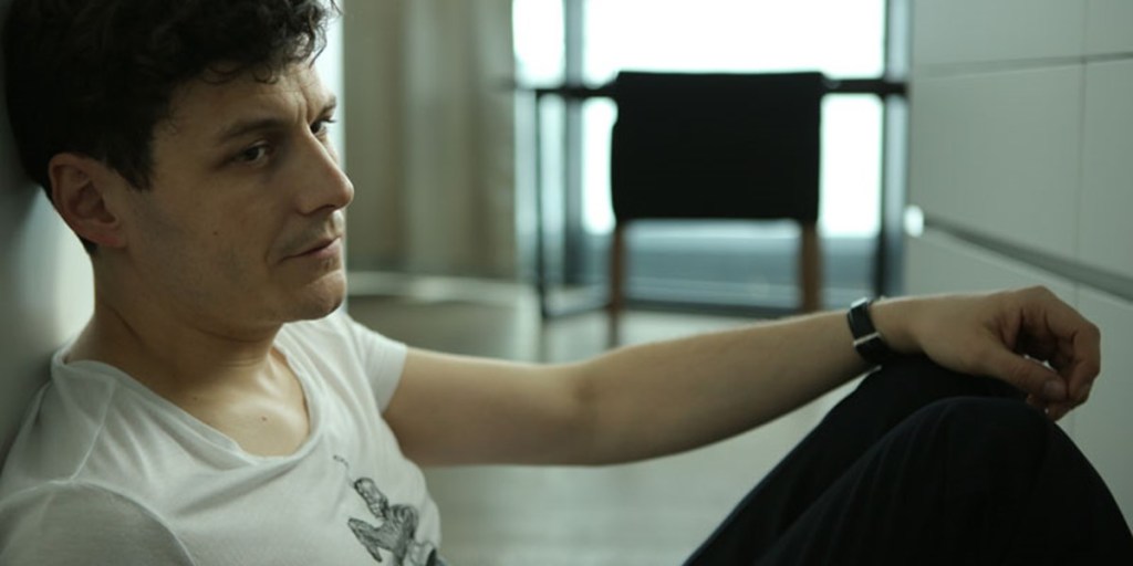 Gruber (Manuel Rubey) sitting on the floor, looking sad.