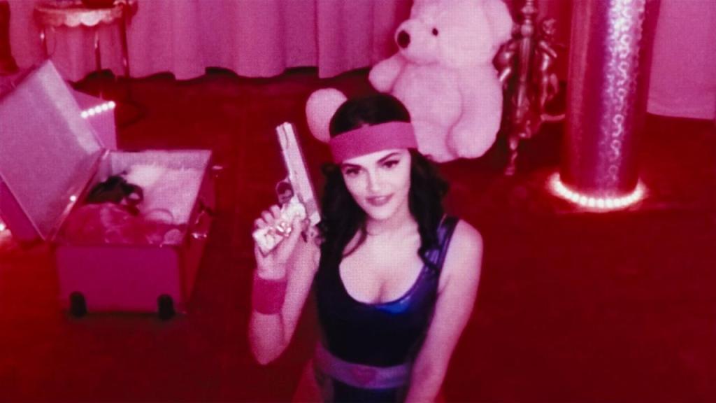 Alice (Madeline Brewer) in an 80s aerobics outfit holding up a gun.